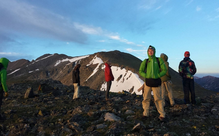 a group of people stand atop a rocky landscape looking in different directions 